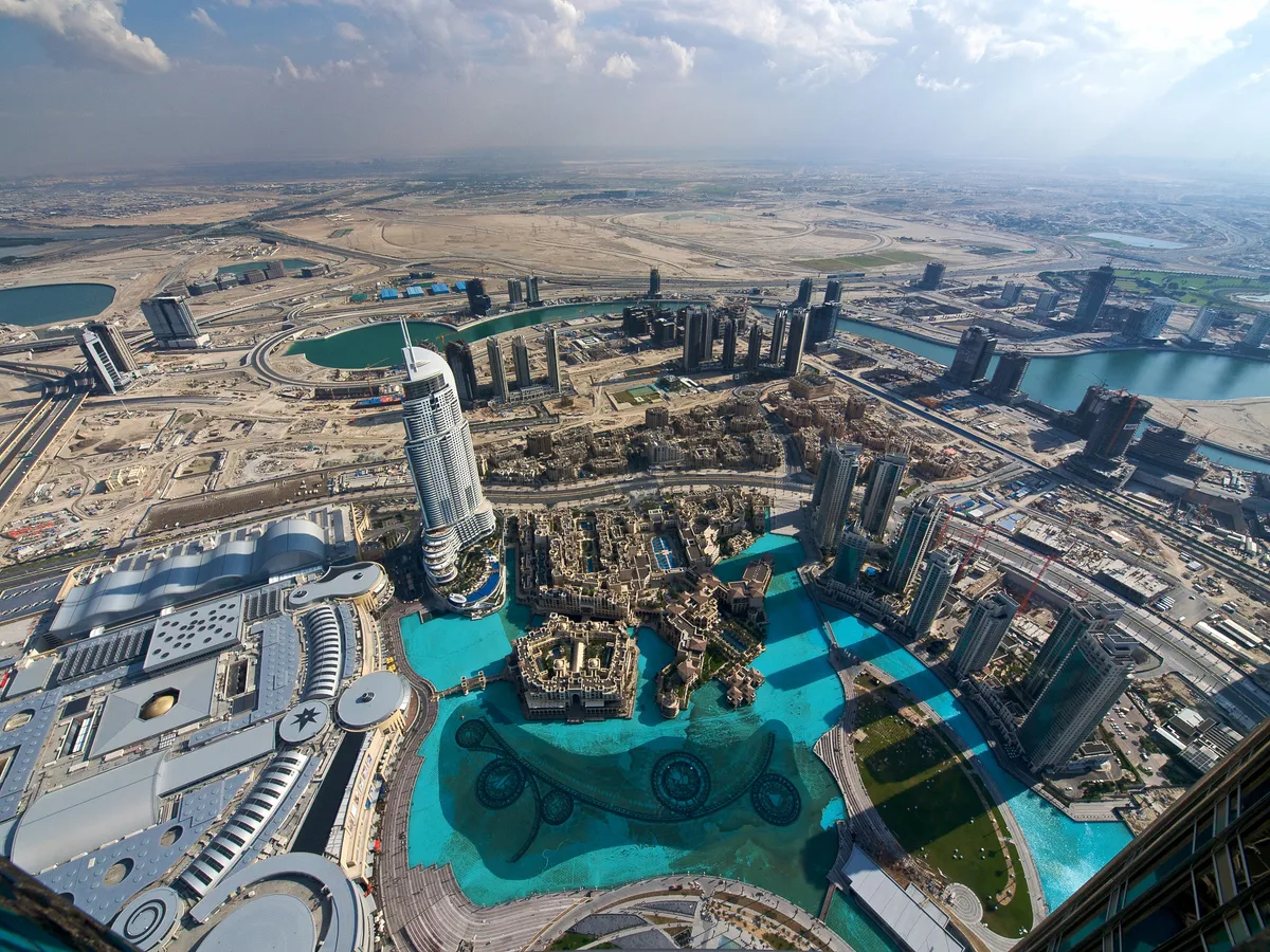 Downtown Dubai from high above, towers around the turquoise lake of the Dubai Fountain
